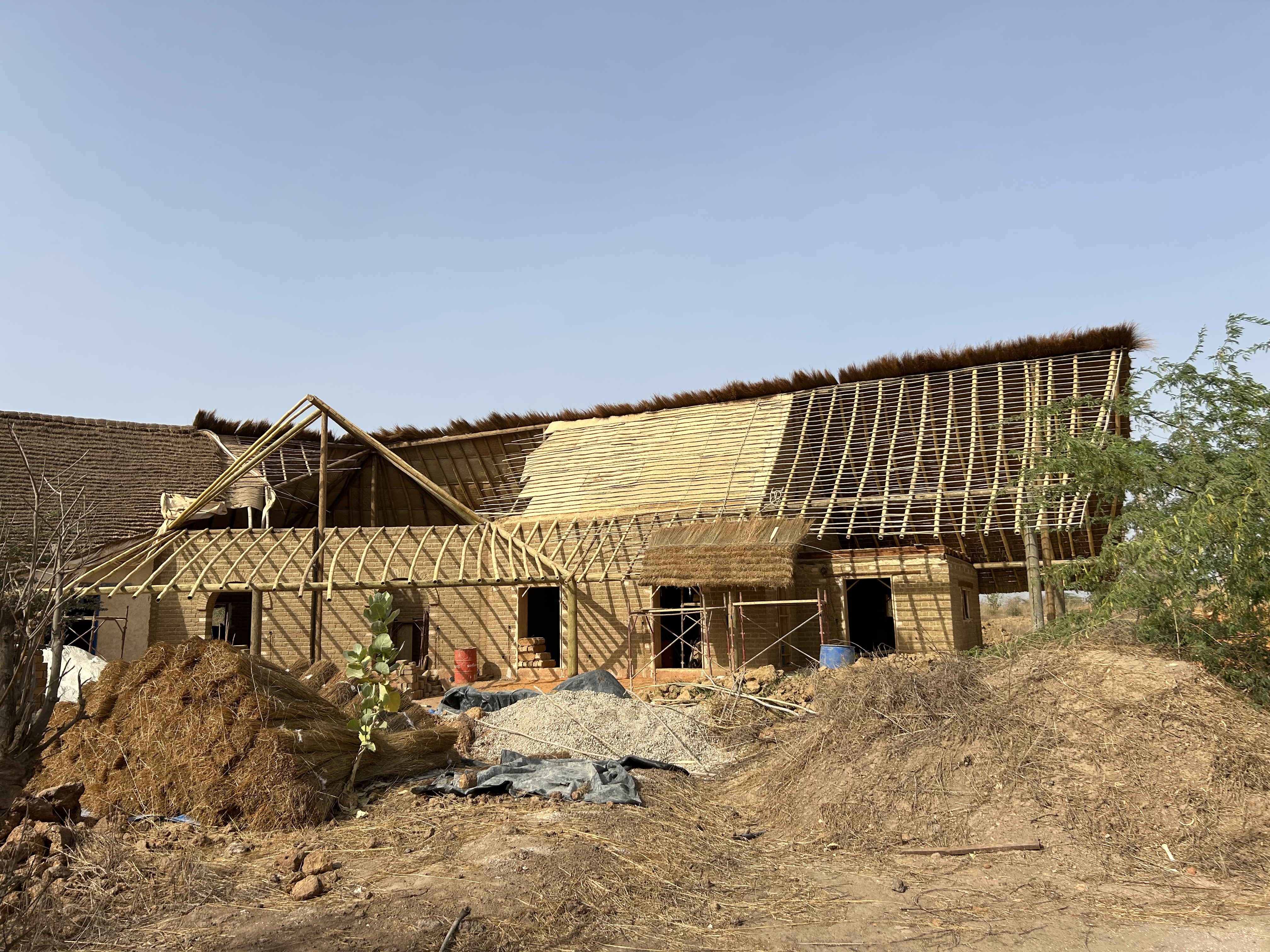 Full view of the construction site — adobe walls and bamboo frame